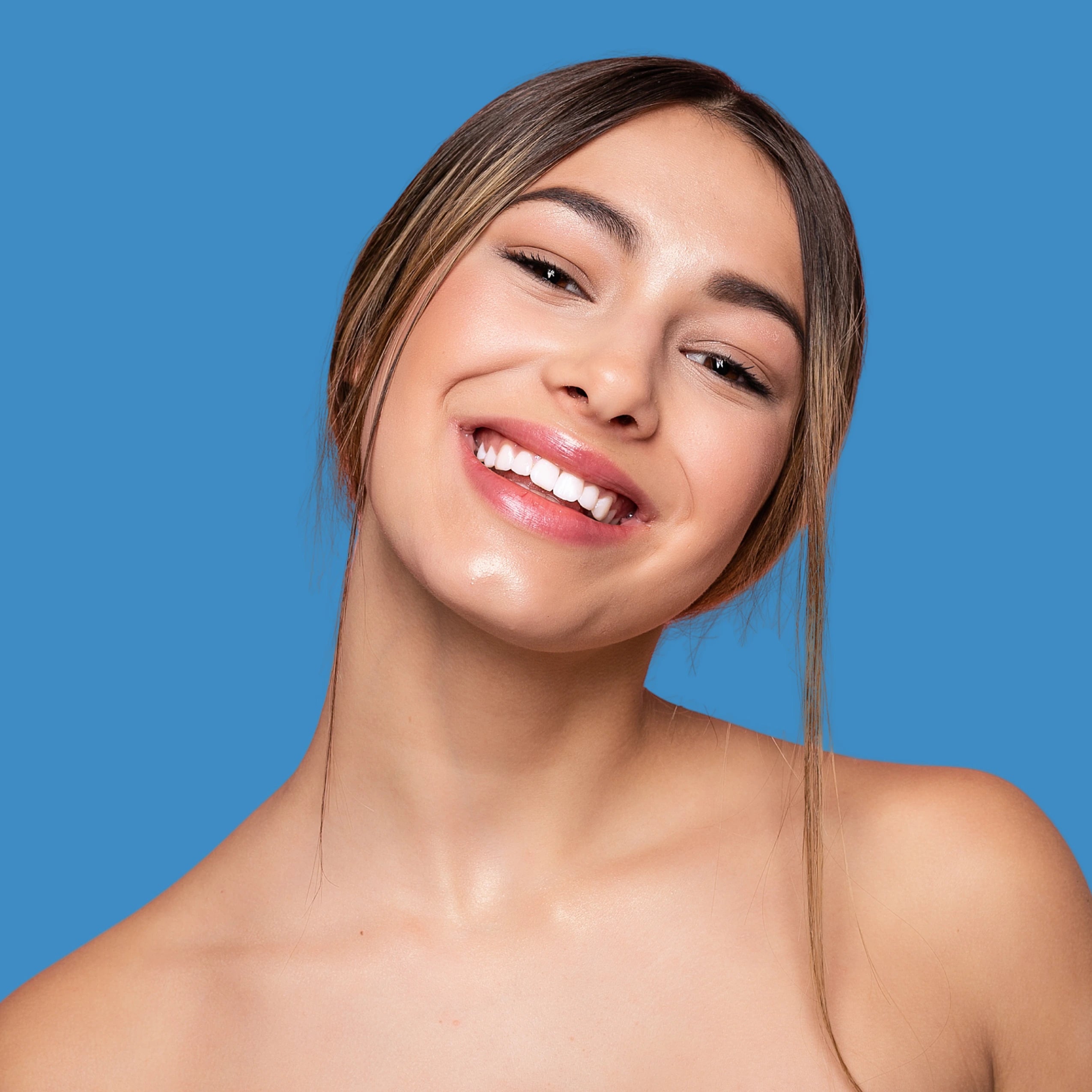 Woman with a bright smile and clear skin against a blue background
