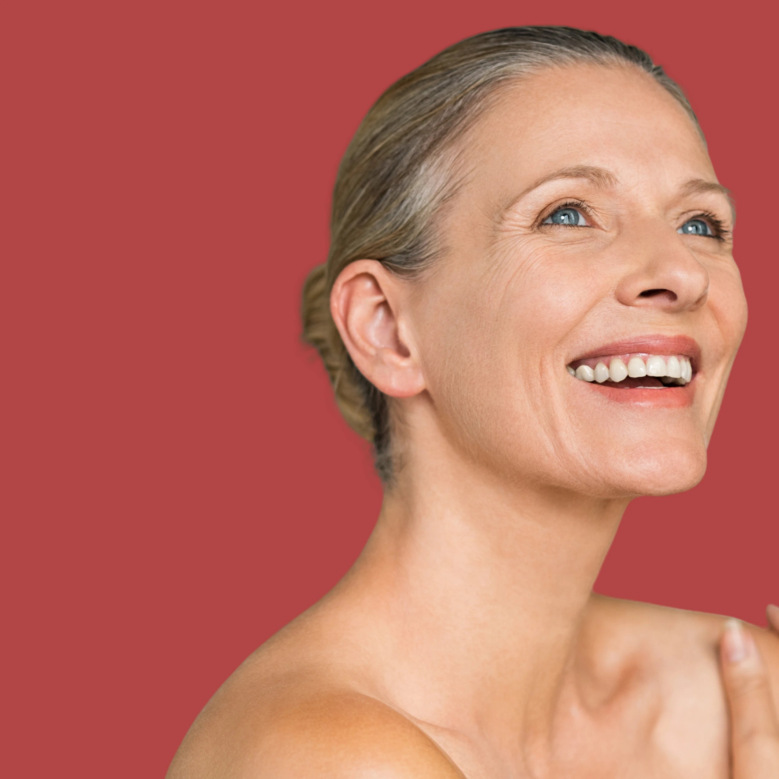 Woman with a bright smile and smooth skin against a red background