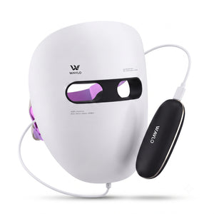 A white LED facial therapy mask with purple light visible through the eye cutouts, shown with a black oval control unit and white cables on a clean white background. The brand name 'WAVLO' is visible on both the mask and the control unit.